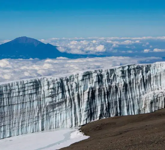 Glacier on Mount Kilimanjaro with a view of the summit and clouds in the background.