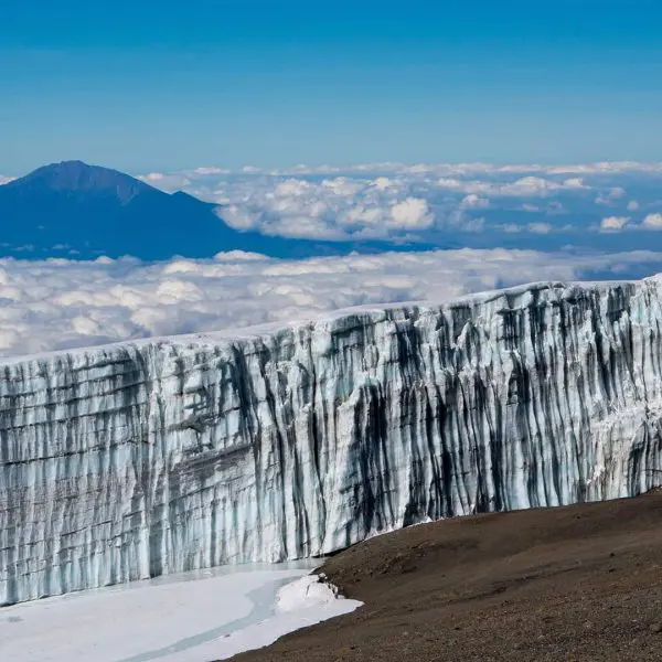 Glacier on Mount Kilimanjaro with a view of the summit and clouds in the background.