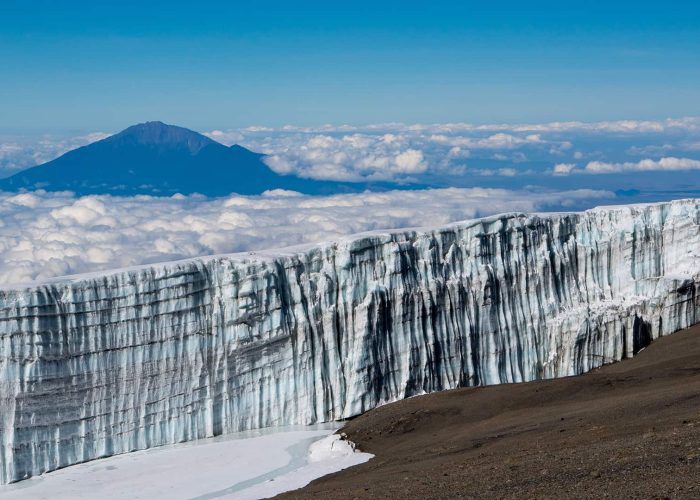 Glacier on Mount Kilimanjaro with a view of the summit and clouds in the background.