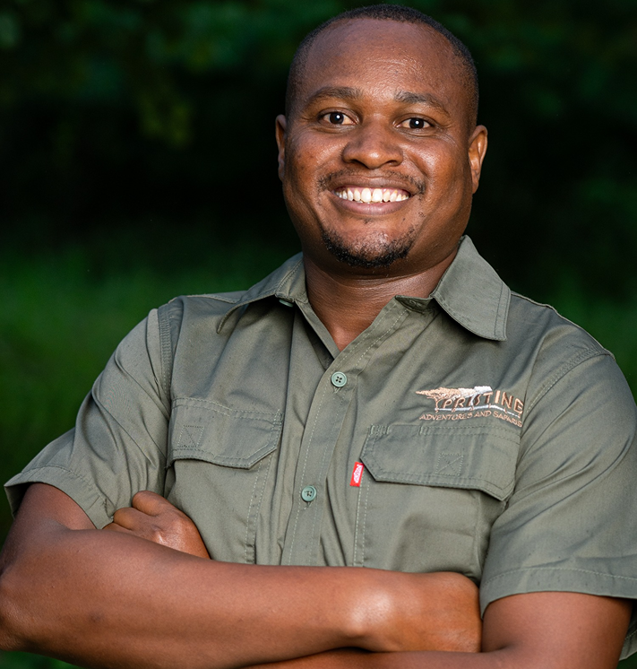 Meet the Team: A man in a green short-sleeve shirt stands outdoors with arms folded, smiling at the camera.